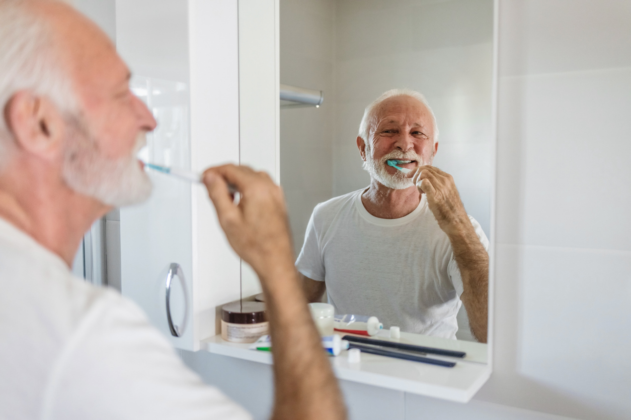Cropped shot of a mature man brushing his teeth in his bathroom at home, daily routine.